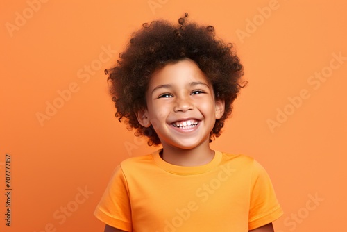a professional portrait studio photo of a cute black boy child model with perfect clean teeth laughing and smiling. isolated on orange background. for ads and web design © JAYDESIGNZ