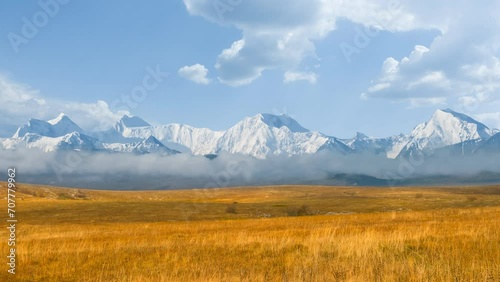 autumn prairie with dry grass and snowbound mountain chain in a mist beyond time lapse scene photo