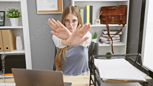 Angry expression of young blonde business worker woman in office, rejecting with crossed arms and palms in negative sign photo