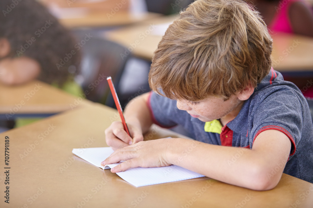 School, boy and writing in book in classroom, desk and studying for education, knowledge and learning assessment. Child, kid and student drawing in notebook for academic development, test and lesson