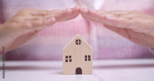 Hands hovering over a tiny wooden house manifesting a desire of owning a house and lot real-estate property. photo