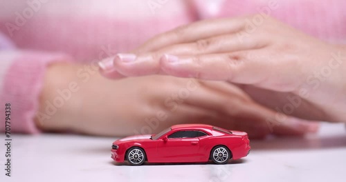 Hand hovering over a red toy sportscar, manifesting the desire to own a new vehicle through a car bank loan. photo