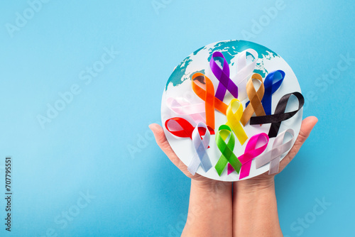 World cancer day February 4. Hand holding colorful awareness ribbons on world map. Healthcare and medical concept.Banner