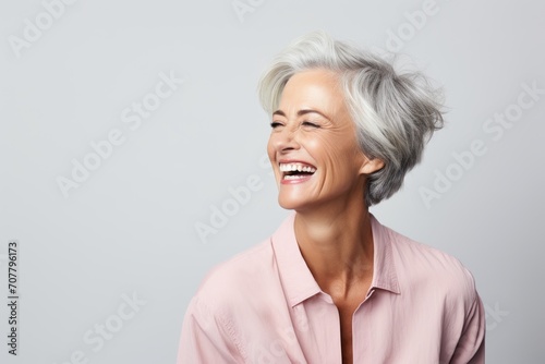 Portrait of happy senior woman laughing and looking up over grey background