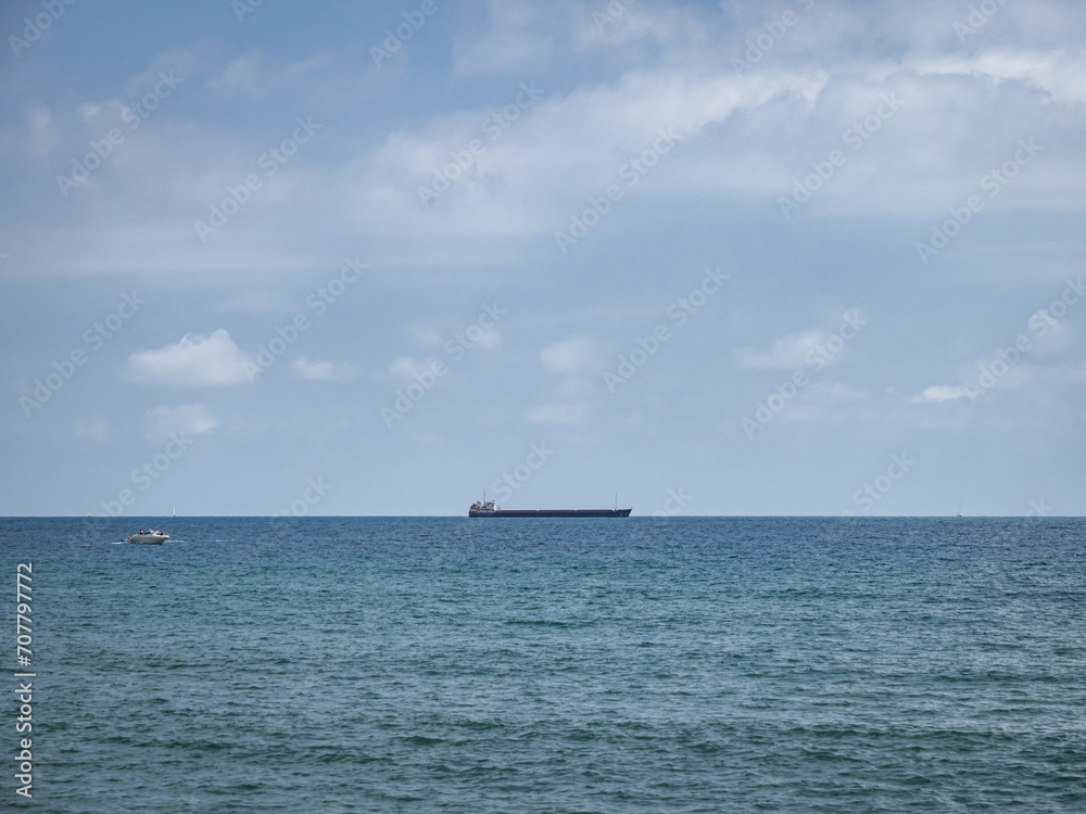 A container ship and a yacht on the sea horizon on the Mediterranean Sea off the coast of Málaga, Spain