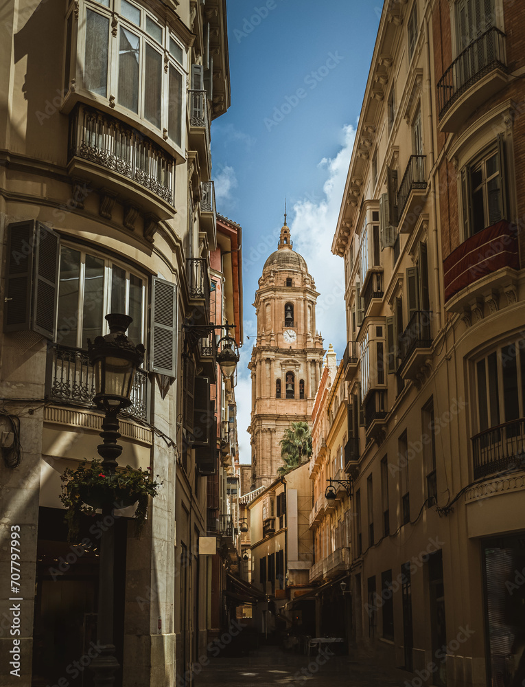 Clock Tower of the Cathedral of Malaga, view from a narrow street between houses