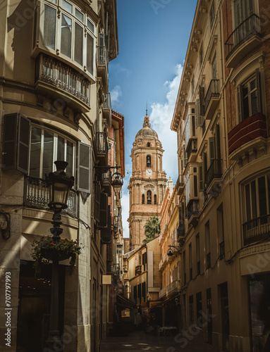 Clock Tower of the Cathedral of Malaga, view from a narrow street between houses