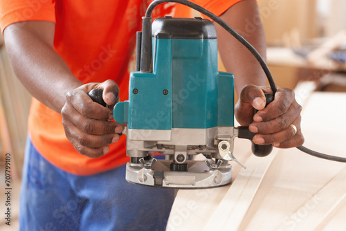 african carpenter using a router to make the edge on a plank