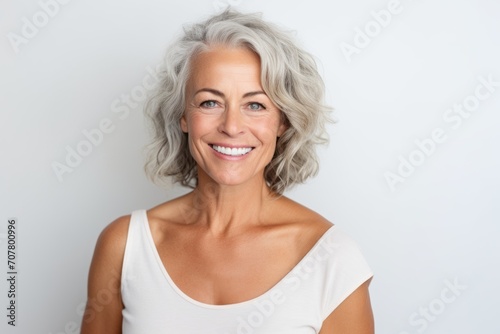 Beautiful mature woman. Portrait of beautiful mature woman looking at camera and smiling while standing against grey background