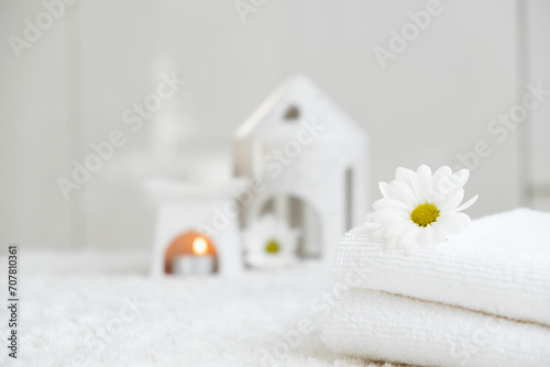 White towels with chamomile and aroma lamp, candle on background. Spa therapy and wellness, aromatherapy relaxation. Massage salon or beauty salon. Body care and treatment. Self Love. Copy space.