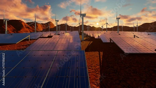Rotating windmills and solar panels at sunset