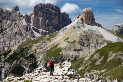 Stunning view of a tourist and his dog enjoying the view in the Tre Cime Di Lavaredo National park, Dolomites, Italy.