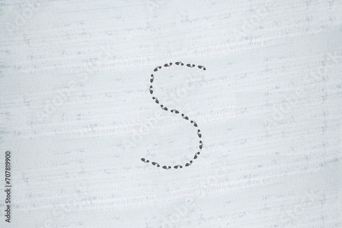 The letter S written in the snow. Winter writings.