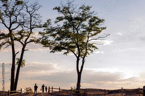 A family of three is walking from the Lake Ontario beach to the Toronto Islands at sunset.