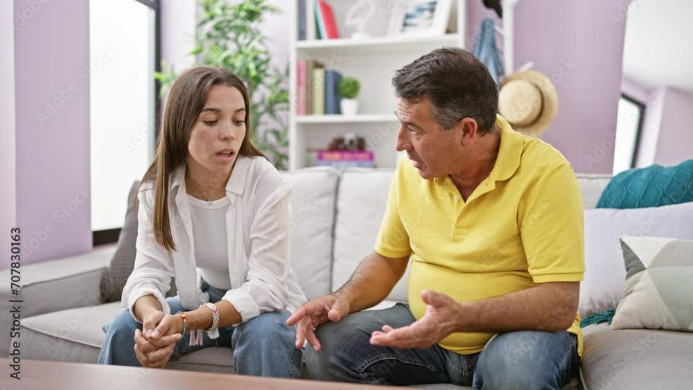 Father and daughter sitting on sofa together speaking at home Father and daughter sitting on sofa together speaking at home
