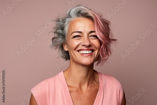 Portrait of a happy senior woman with pink hair over pink background