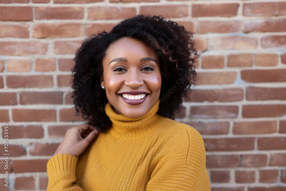 Curly African American woman wearing yellow shirt against red brick wall background Curly African American woman wearing yellow shirt against red brick wall background