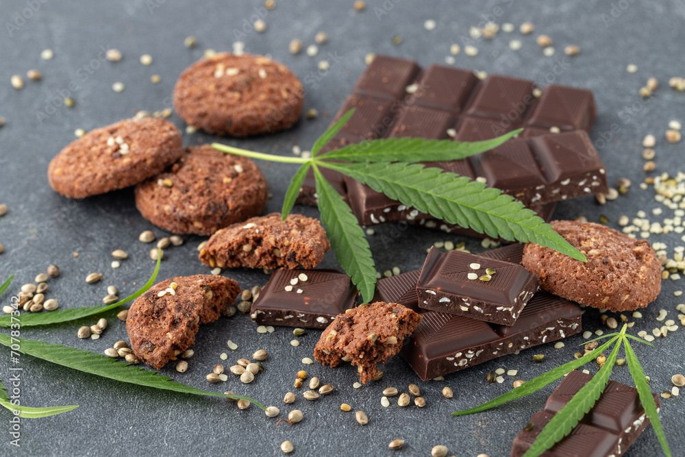 Φωτογραφία Cannabis leaves, chocolate bar and cookies infused  crushed hemp seeds and cbd oil closeup on  dark grey stone table
