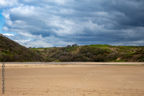 A ruin on top of Three Cliffs Bay as seen from the beach