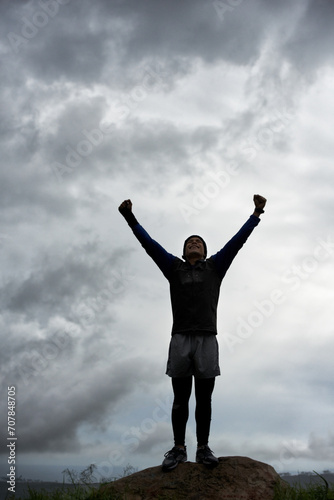 Happy man, mountain peak or hands up for celebration in training, exercise or workout success. Excited athlete, sky or healthy hiker with cheering, gratitude or freedom in nature for fitness