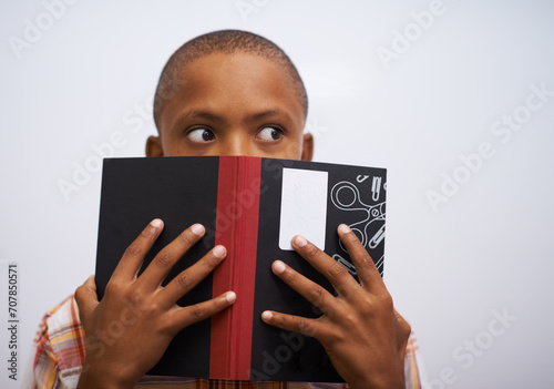 Student, classroom and hide face with book to read in front for classmates, shy and learning. Elementary school, boy and prepared oral with workbook, childhood development and academic education