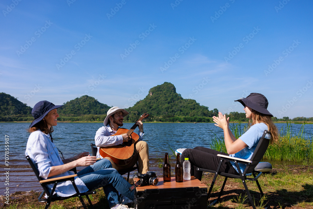 happy family playing guitar and sing a song at the campground by the riverside,