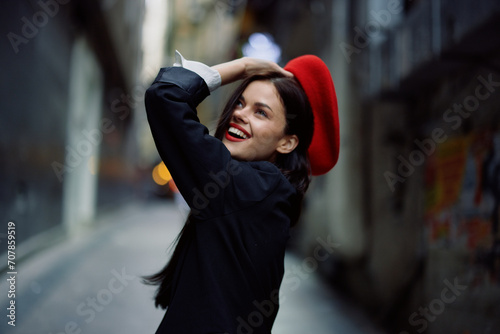 Fashion woman smile with teeth and fun tourist in stylish clothes in jacket and red beret walking down narrow city street flying hair, travel, French style, cinematic color, retro vintage style.