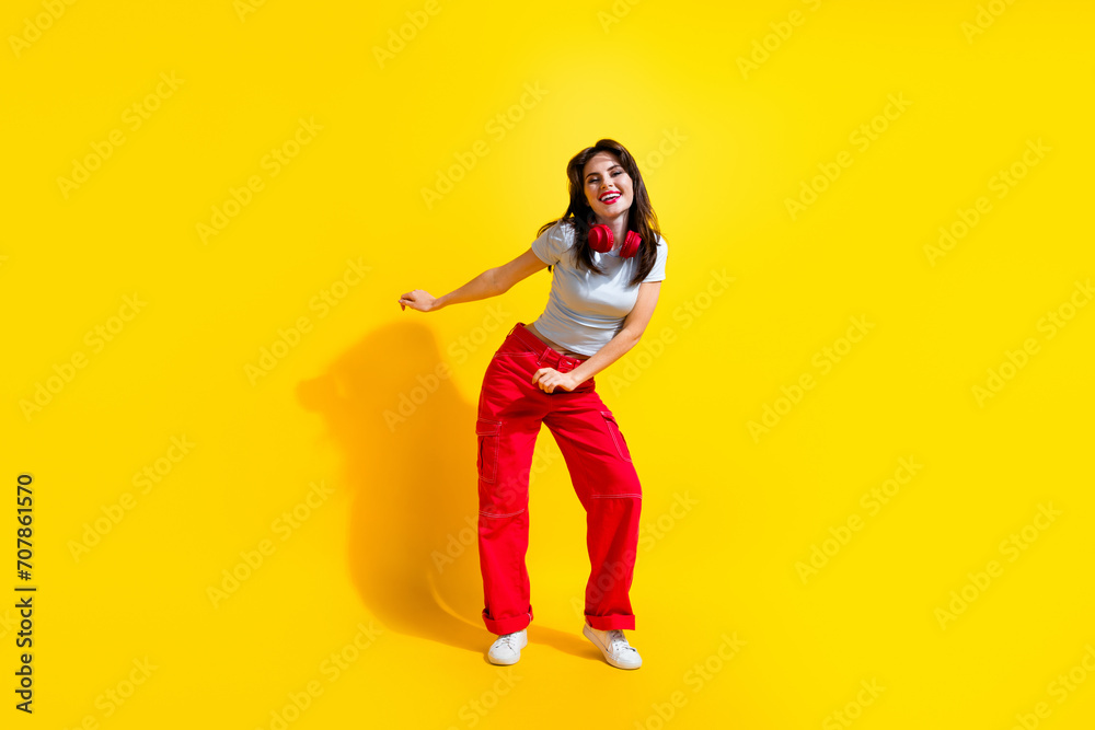 Full length photo of positive shiny lady wear white t-shirt earphones enjoying disco isolated yellow color background Full length photo of positive shiny lady wear white t-shirt earphones enjoying disco isolated yellow color background