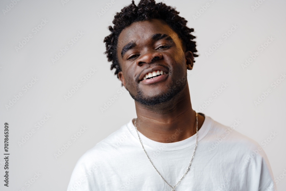 Portrait of a smiling young african man wearing white t-shirt standing over gray background Portrait of a smiling young african man wearing white t-shirt standing over gray background