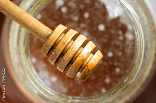 honey dipper close up with the organic product on background unfocused