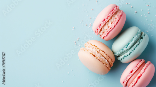 French cake macaron or macaroon on a turquoise background from above. Colorful almond cookies in pastel colors create a vintage card or cake shop banner. Top view, flat-lay, pale blue with copy space photo