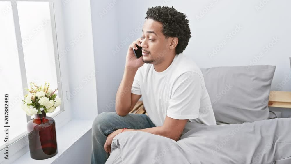 African american man talking on phone relaxed in a bright bedroom African american man talking on phone relaxed in a bright bedroom
