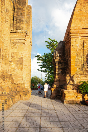 Tourists taking picture at narrow space between North Tower or Thap Chinh and Central Tower or Thap Nam of Ponagar Cham Towers, terraced pyramidal roof, built partly of recycled bricks photo