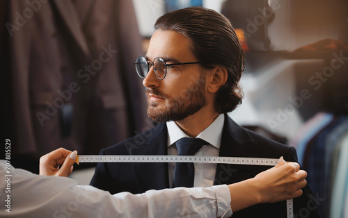 Banner Atelier Classic Menswear. Woman tailor taking measurements of young handsome man, fitting bespoke suit to model photo