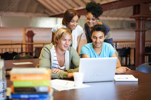 Teamwork, laptop or group of students studying in university, college or school campus for education. Library, elearning or happy people with scholarship, reading news, research or online course photo