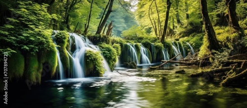 Plitvice National Park on a bright summer day with blue sky and clouds and green foliage and turquoise water