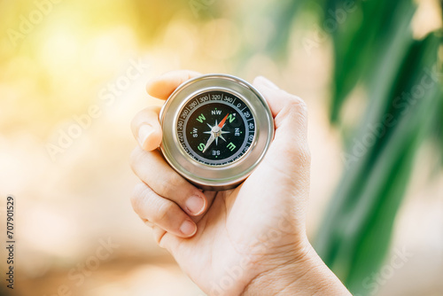 Traveler holds a compass in a park finding her way amidst confusion. The compass in her hand symbolizes guidance exploration and the journey to conquer defeat.