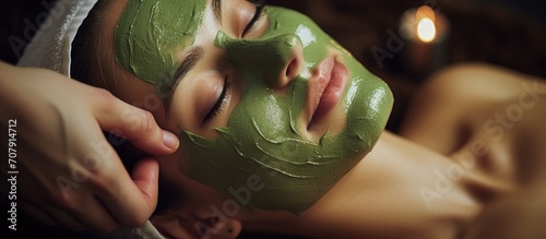 Woman getting rejuvenating green peel facial mask in a spa salon. photo