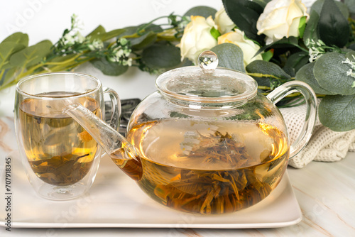 Teapot and glass cup with blooming tea flower