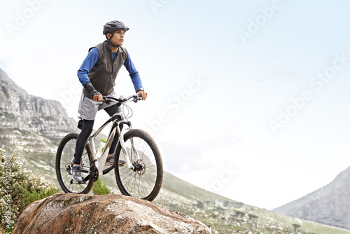 Man, mountain bike and off road cycling with mockup space on nature adventure or fitness in outdoor extreme sport. Male person or cyclist on bicycle for cardio on cliff hill in exercise with blue sky © Alexandra/peopleimages.com