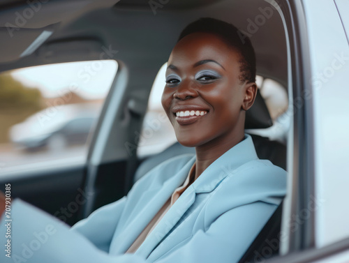 a happy stylish african woman in light blue suit is driving white car. Portrait of happy female driver steering car with safety belt.
