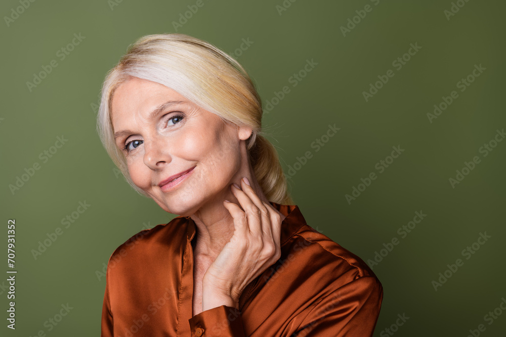 Photo portrait of pretty retired female skincare touch neck charming dressed stylish silk brown outfit isolated on khaki color background Photo portrait of pretty retired female skincare touch neck charming dressed stylish silk brown outfit isolated on khaki color background