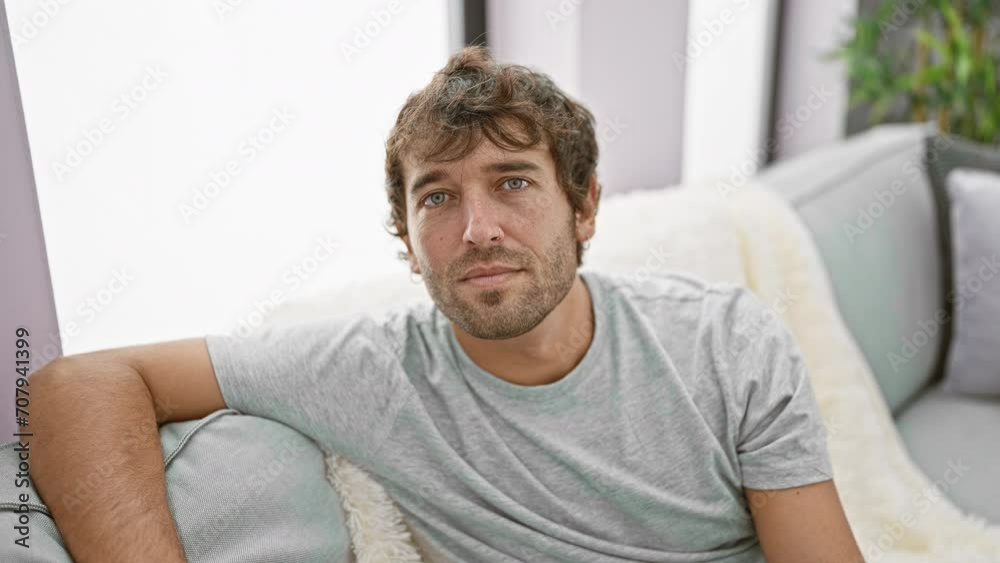 Young man sitting on the sofa with serious expression on face. simple and natural looking at the camera. at home Young man sitting on the sofa with serious expression on face. simple and natural looking at the camera. at home