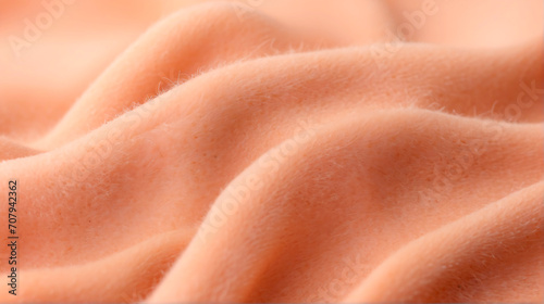 A close up of a peach colored fabric. Monochrome peach fuzz background.