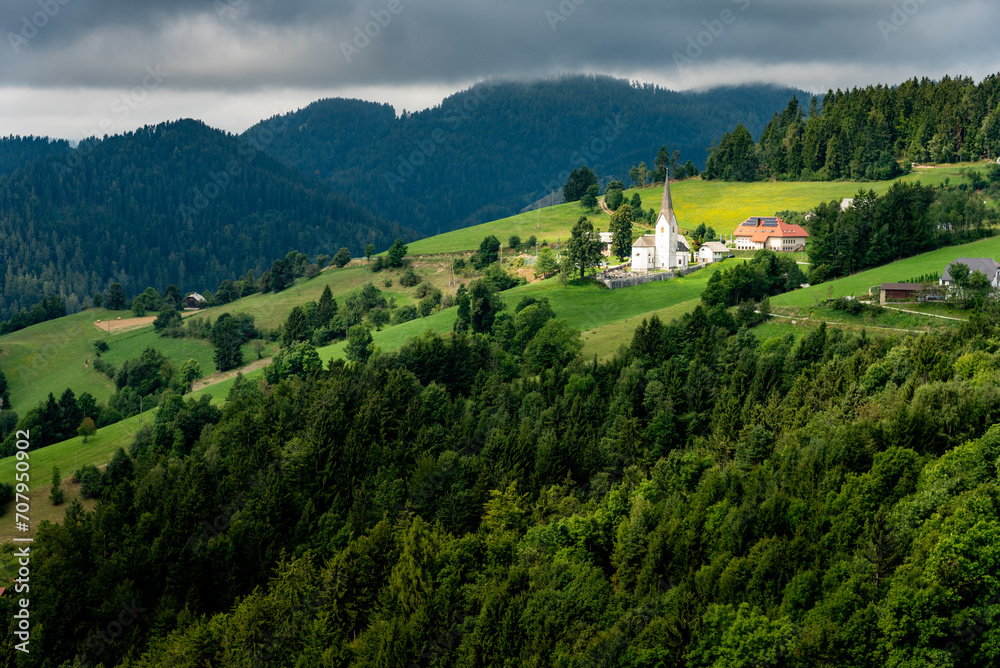 Landscape of Slovenia. A small church in the middle of the fields behind a forest