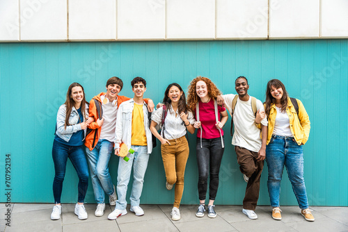 Diverse college students standing together on a blue wall - Photo portrait of multiracial teenagers in front of university building photo