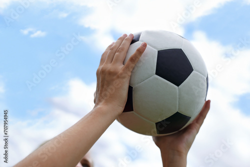 Hands, blue sky and closeup of ball for soccer exercise, game or training in outdoor field. Sports, fitness and zoom of person holding equipment for football match or workout in park or pitch. © Tasneem H/peopleimages.com