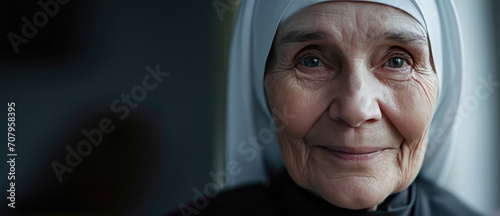 Serene Joy of Devotion. Old nun smiling, portrait with copy space on grey background. photo
