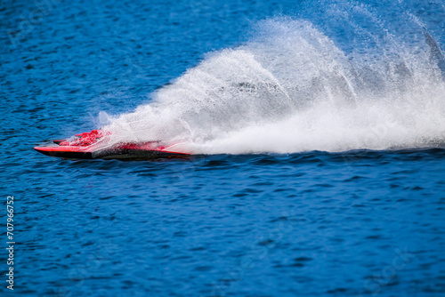 RC racing boat straightaway skips across the water leaving behind huge spray and ripples.