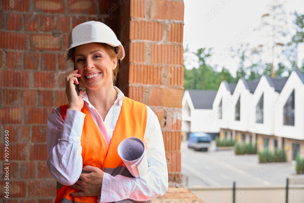 Joyful construction manager having phone conversation on development site Joyful construction manager having phone conversation on development site